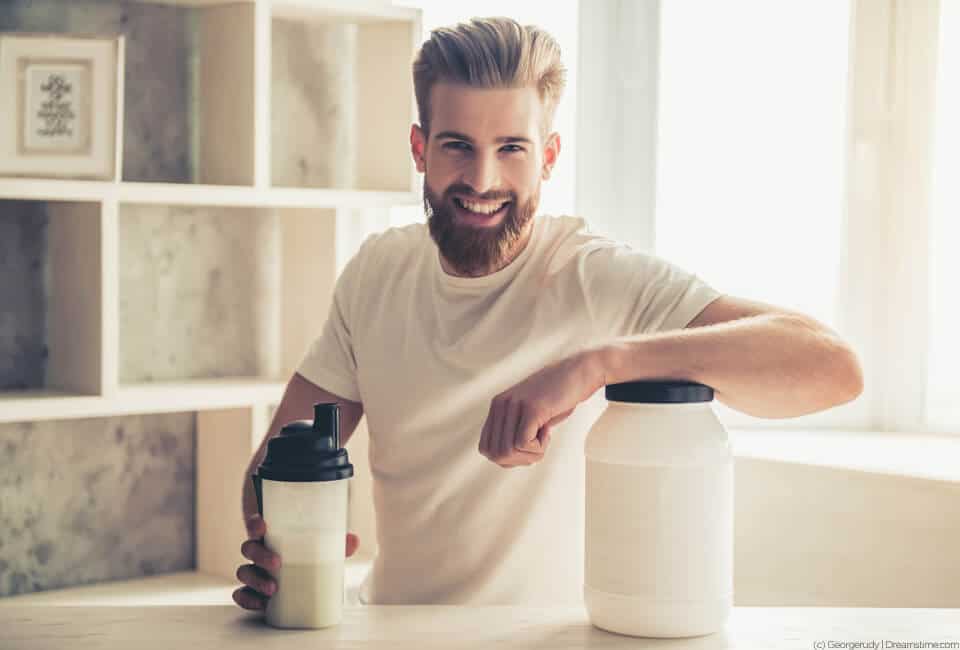 Male leaning on his pre-workout supplement container