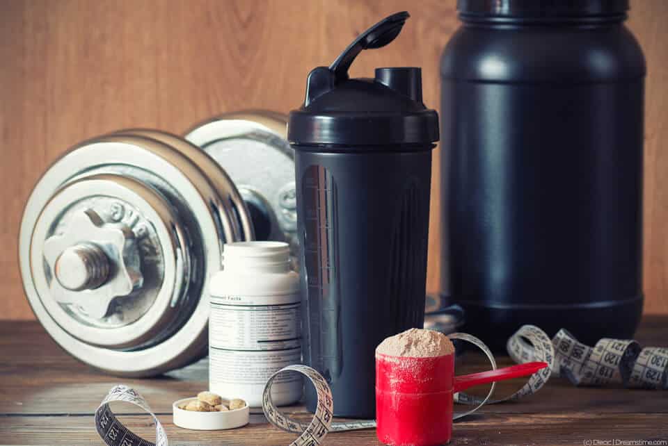 Dumbbell, shaker bottle and various fitness supplements