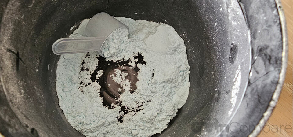 The inside of an open tub of creatine with a scoop inside.